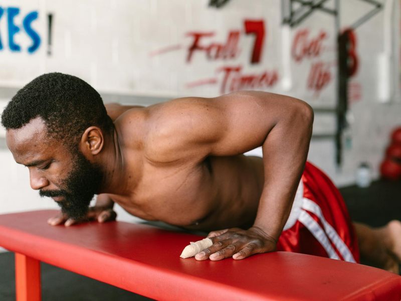 Man performing a controlled bodyweight squat in a bright, minimalist gym.